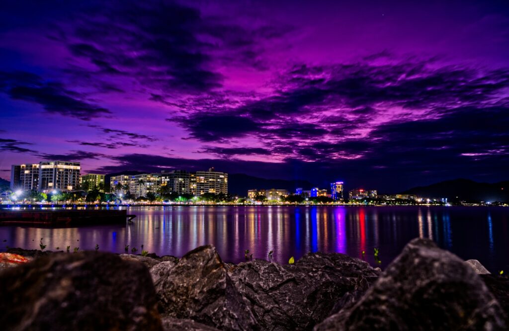 Things to do in Cairns, Cairns accommodation, grey seashore rock with view of city skyline during night time