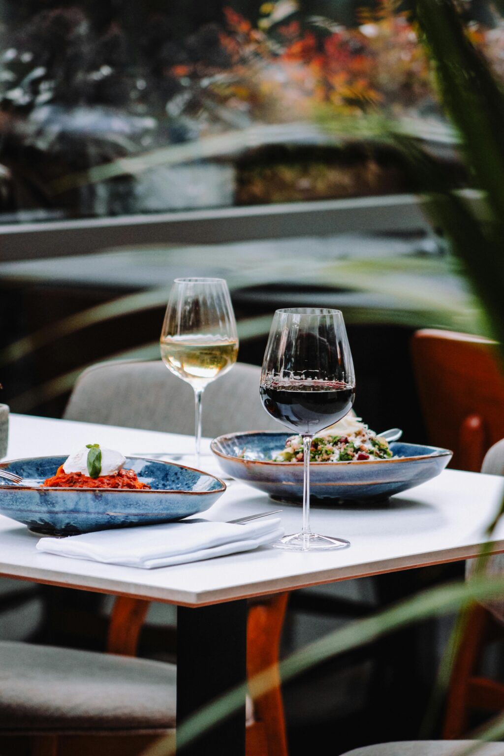 Luxurious outdoor dining setup with red and white wine, plated dishes, and elegant ambiance.