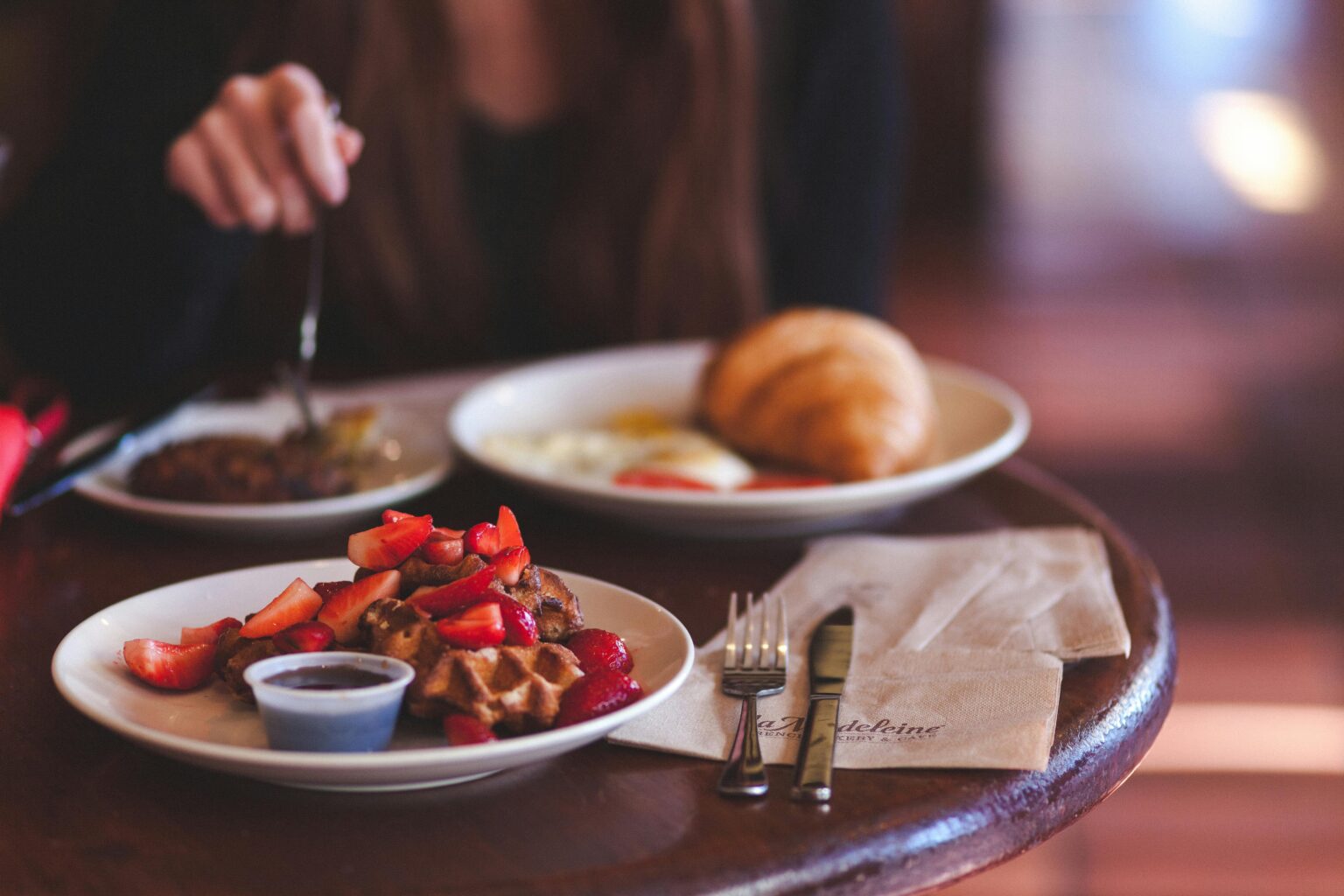 Enjoy a delicious brunch featuring waffles topped with fresh strawberries and a side of jam.