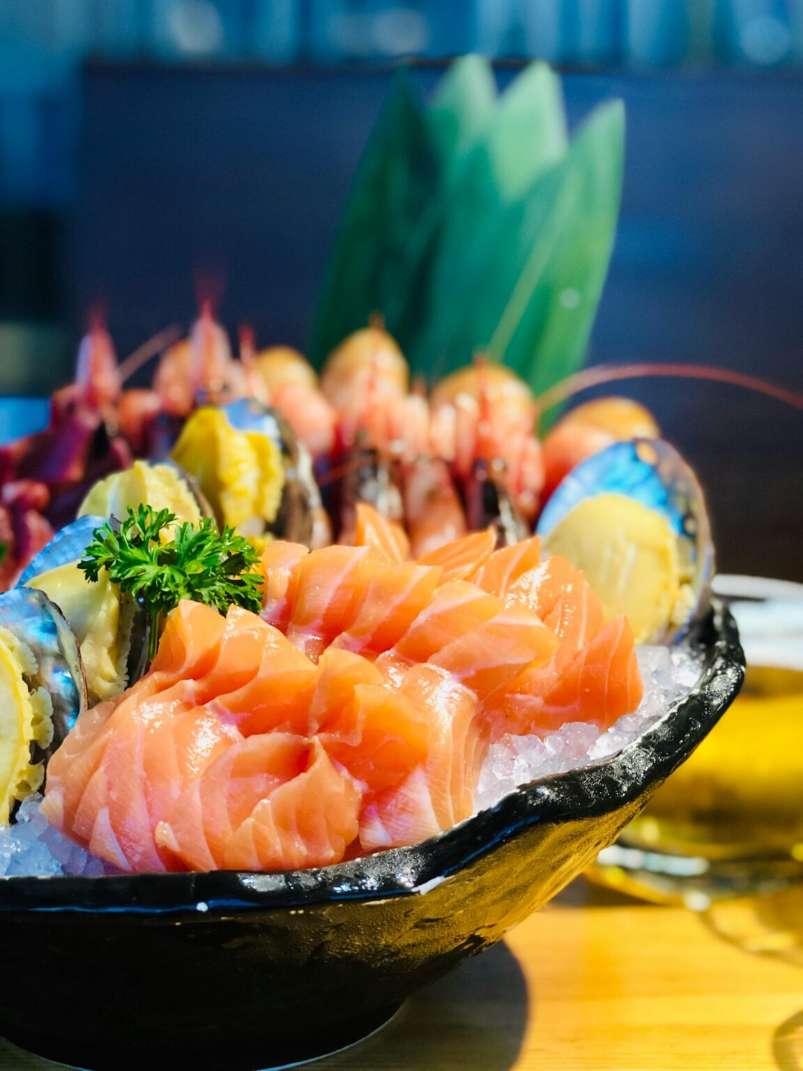Best restaurants in Cairns, Close-up of a traditional sashimi platter showcasing fresh salmon and seafood on ice garnished with parsley.